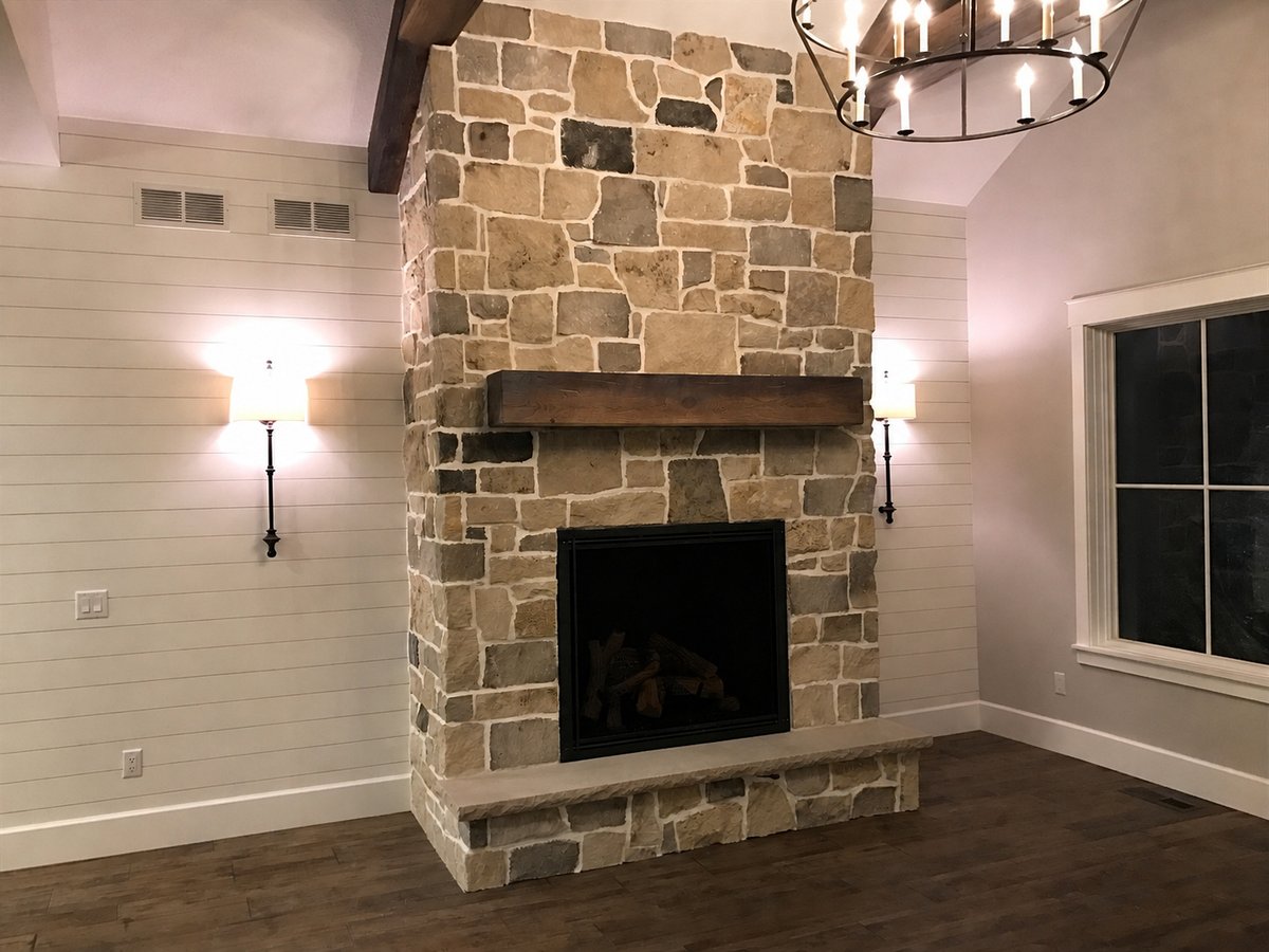 Open great room with a stone fireplace and wood floors