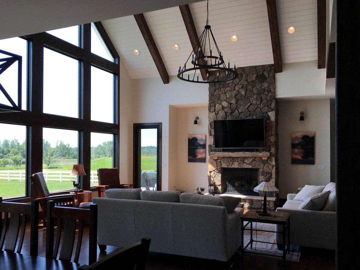 Vaulted great room with timber beams and a wall of windows